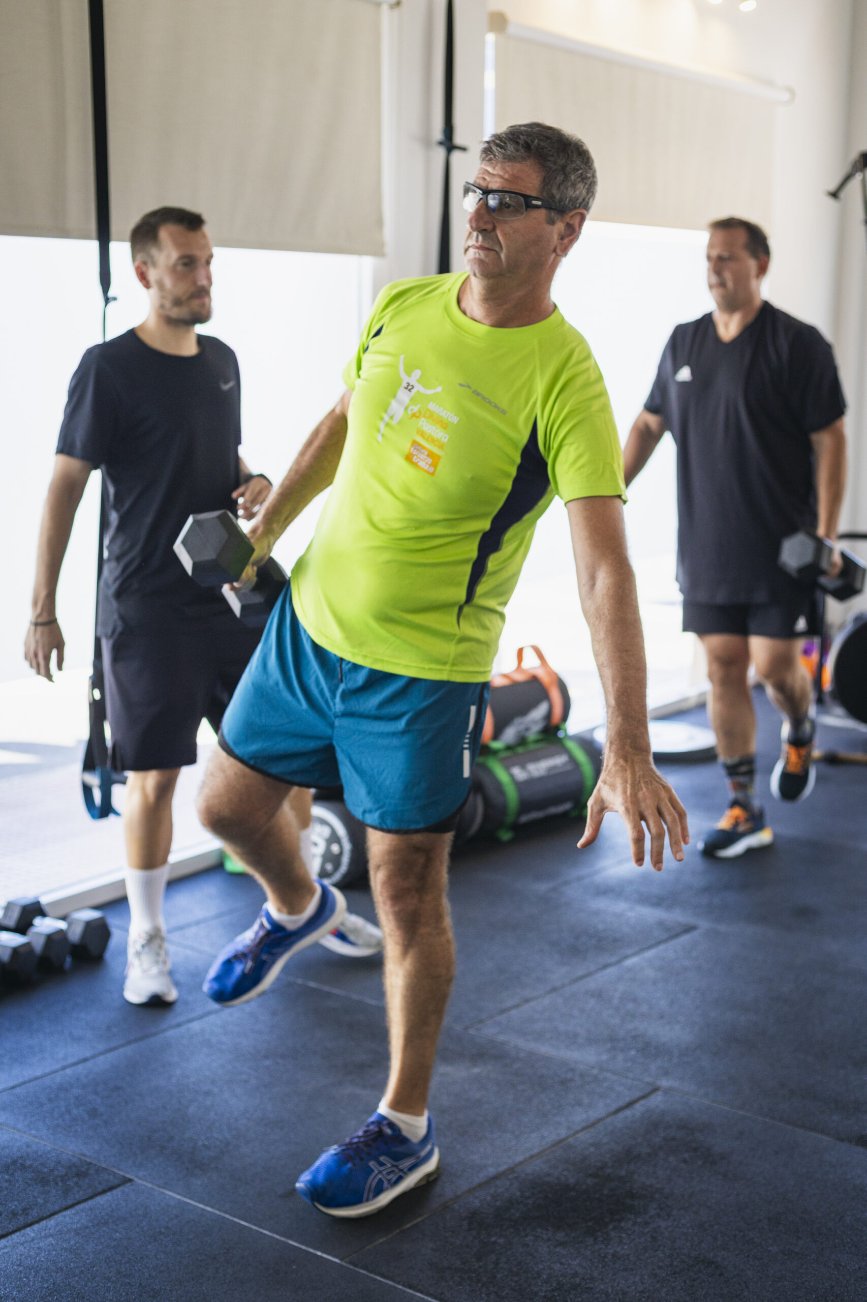 Entrenamiento funcional de equilibrio y fuerza con mancuernas en gimnasio. Persona realizando ejercicio de estabilidad para cintura y espalda.