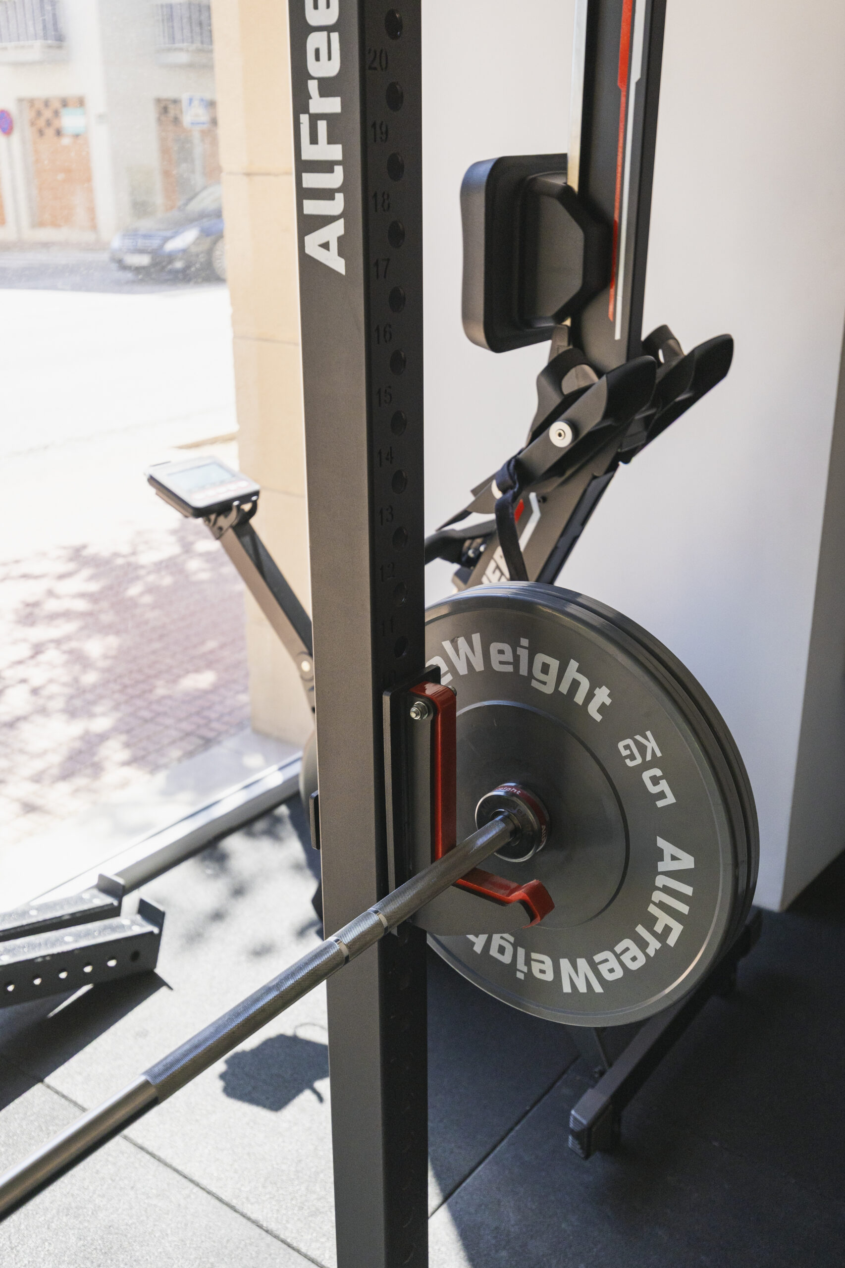 Barra de levantamiento de peso con disco de 5 kg de la marca AllFreeWeight en un rack o máquina de entrenamiento. Primer plano del equipo de fuerza en un gimnasio.
